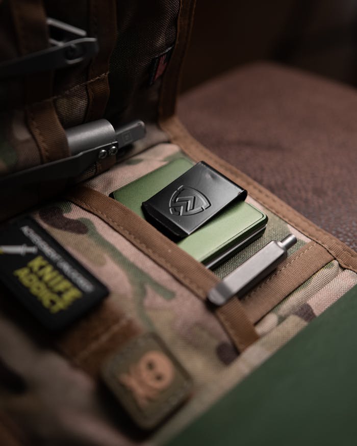 Close-up of tactical gear and wallet in camouflage bag pocket, showcasing EDC essentials.